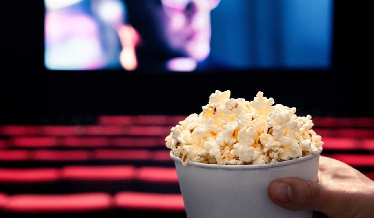 O persoană ține popcorn în mână la cinema