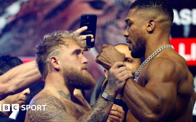 Jake Paul grabs Anthony Joshua's fist during a face-off