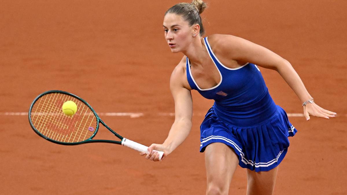 Tenisistka Marta Kostiuk uderza piłkę rakietą podczas meczu na kortach ziemnych.